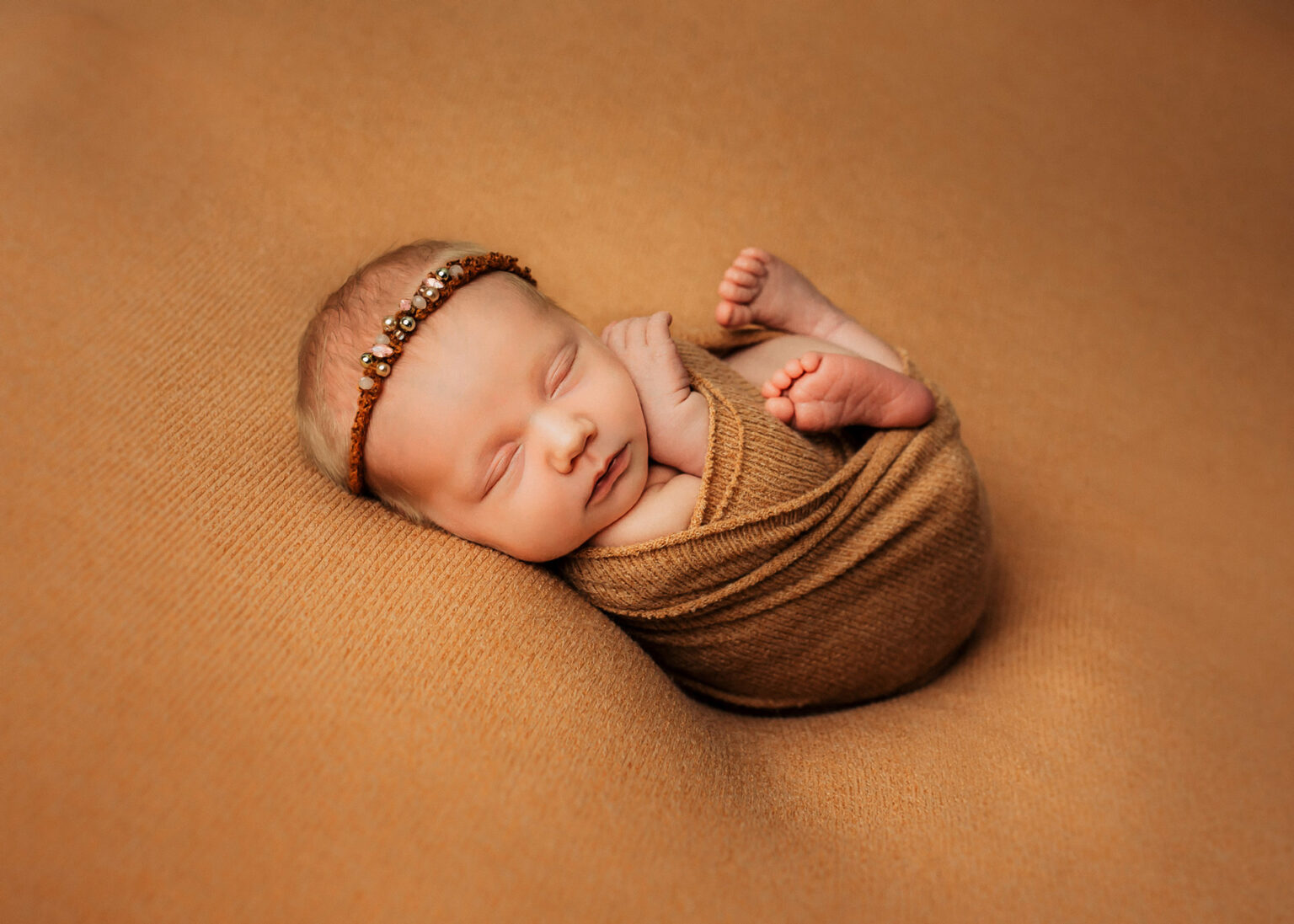 Leipzig Neugeborenenfotos, Baby kuschelig eingewickelt in Tuch liegend auf einer Decke