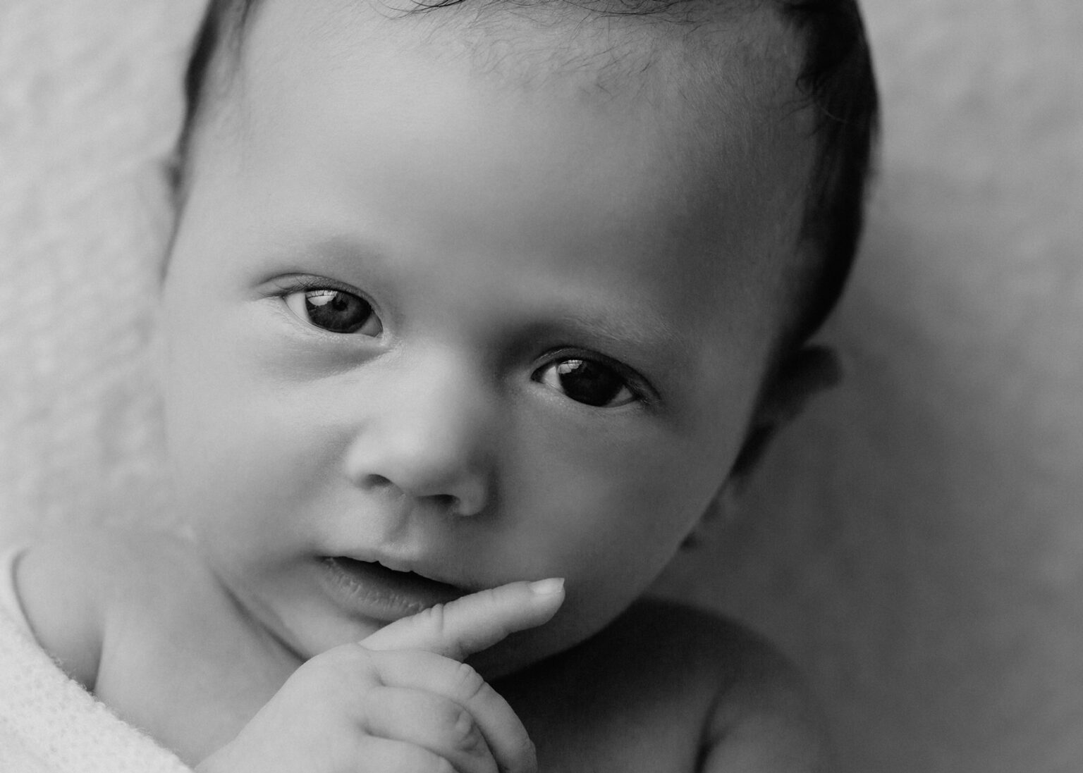 Authentische Babyfotografie Wittenberg, Neugeborenes Baby schaut in die Kamera bei Fotoshooting