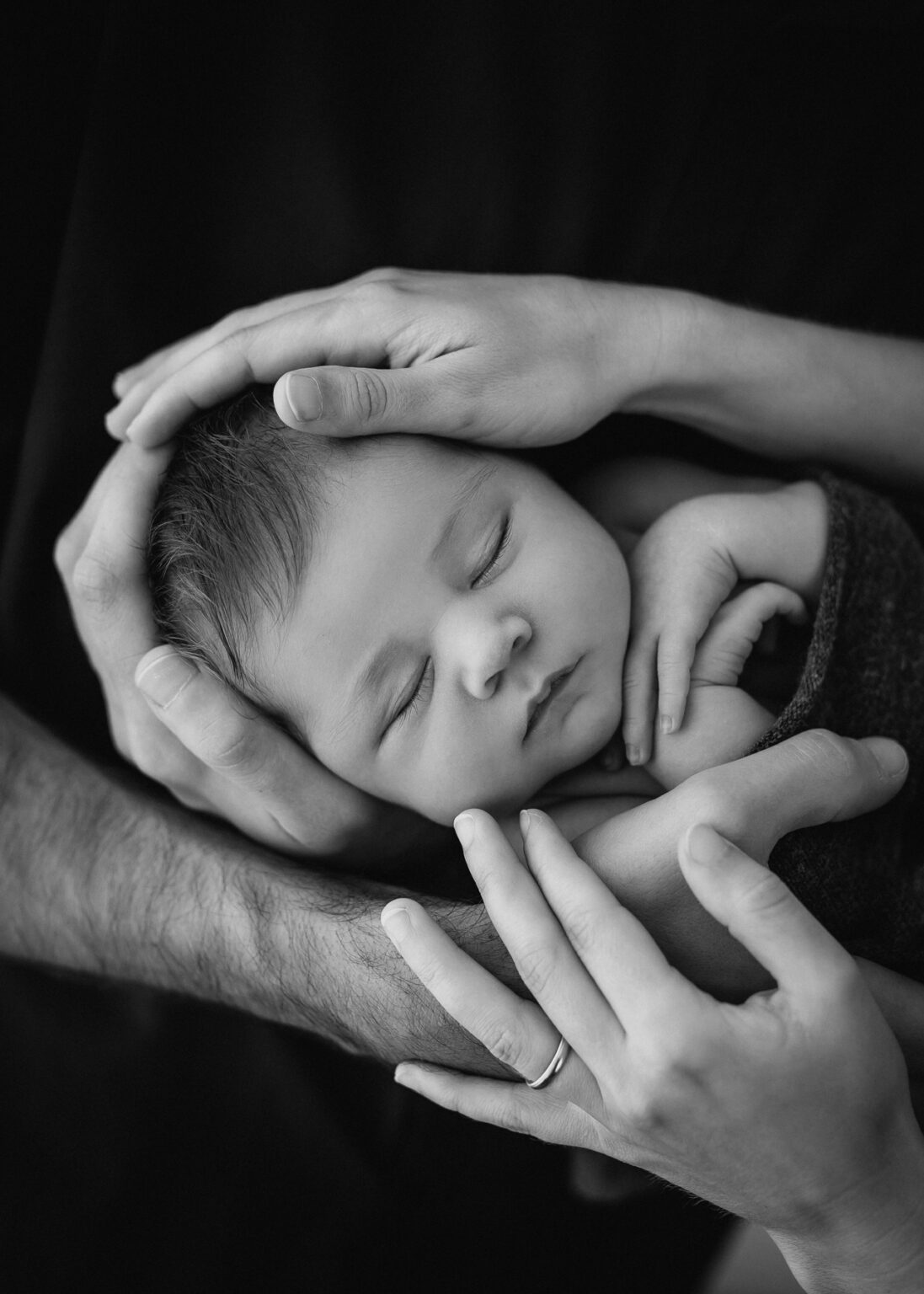 Babyfotografie Leipzig, Eltern halten Neugeborenes Baby im Arm